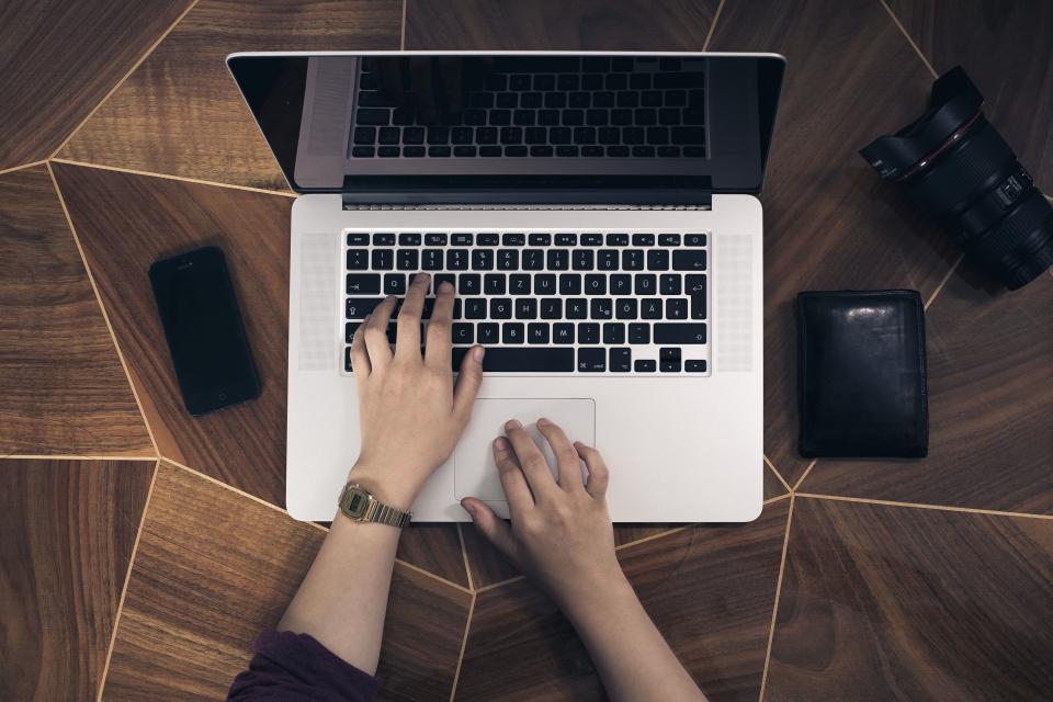 Person working at a laptop with a phone beside it